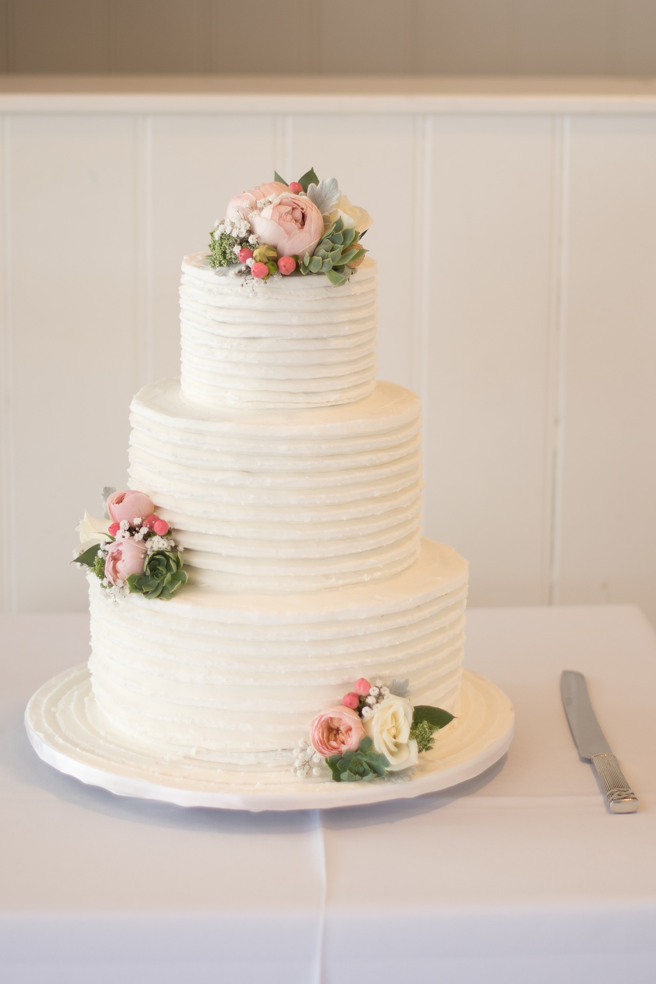 biały tort ślubny z żywymi kwiatami